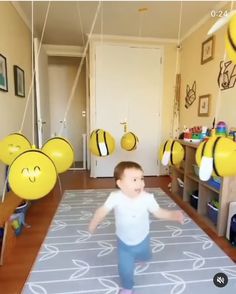 a little boy that is standing in the middle of a room with balloons hanging from the ceiling