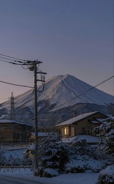 a snow covered mountain in the distance with power lines and telephone poles on either side