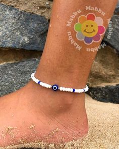 a woman's foot with a blue and white beaded ankle bracelet on it