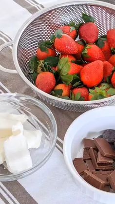 strawberries, chocolate and marshmallows sit in bowls on a tablecloth