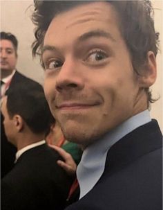 a close up of a person wearing a suit and tie with other people in the background