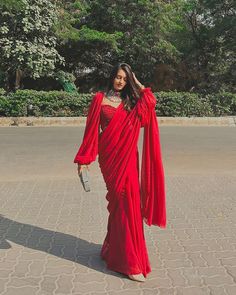 a woman in a red dress is walking down the street with her hand on her hip