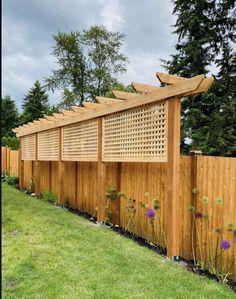 a wooden fence is lined with plants and flowers