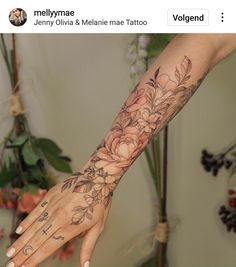 a woman's arm with flowers on it and a cross tattooed on the wrist