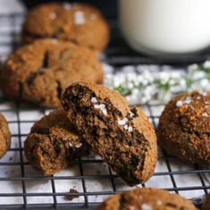 several cookies on a cooling rack next to a glass of milk