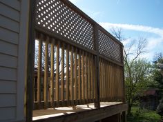 a wooden deck in front of a house on a sunny day with blue sky and clouds