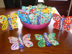 a bowl filled with colorful butterflies sitting on top of a wooden table