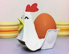 an egg in a carton with a chicken on it next to plates and bowls