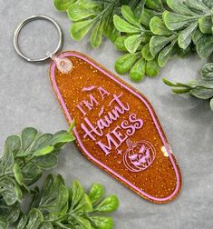 a keychain that says, i'm a happy mess on it next to some plants