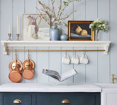 a kitchen counter with pots and pans hanging on the wall above it is an open book