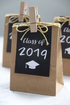 two brown paper bags with black and white graduation tags attached to them, one has a chalkboard sign that says class of 2019