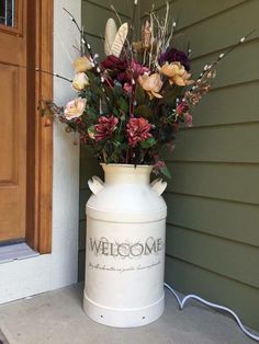 a large white vase with flowers in it sitting on the side of a door way