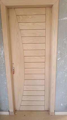 a cat is sitting on the floor in front of a wooden door with slatted panels