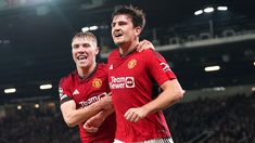 two young men are celebrating at a soccer game, one is holding his arms around the other