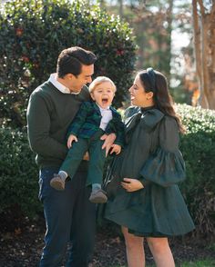 a man and woman holding a baby in their arms while standing next to each other