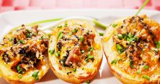 three stuffed potatoes on a white plate with green onions