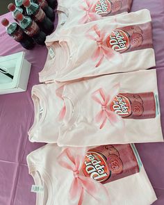 three bottles of soda are sitting on a table with pink cloths and bows around them