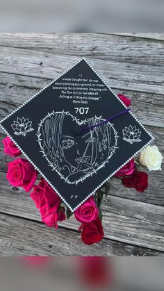 a decorated graduation cap with roses on the table next to it and an image of a couple kissing each other