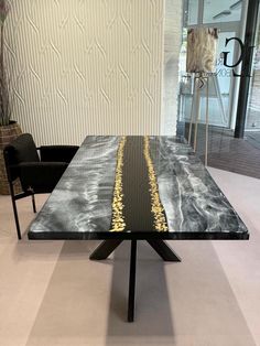 a black table with gold lines on it in front of a glass wall and chairs