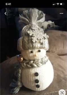 a knitted snowman sitting on top of a couch