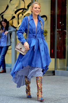 a woman in blue is walking down the street with her purse and handbag on