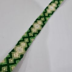 a green and white beaded bracelet on a white surface