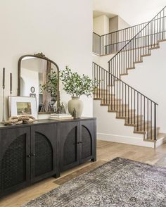 a living room area with a rug, mirror and stairs