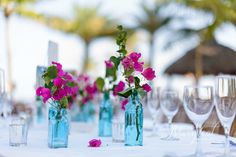 there are many vases with pink flowers in them on the dining table at this wedding reception