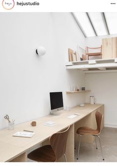 a desk with two chairs and a computer on top of it in a white room