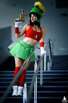 a woman in a green skirt and red top is posing on some stairs with a golden trophy