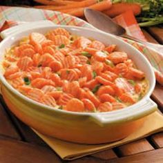 a dish of food on a table with carrots and broccoli in the background