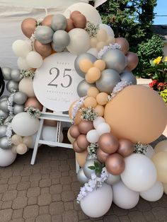 a large number twenty five balloon arch with flowers and balloons on the ground in front of a tent