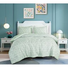 a bed in a room with blue walls and white furniture, including a green comforter