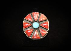 "Navajo Diné Sterling Silver Red Spiny Oyster Shell with Sleeping Beauty Turquoise Statement Ring With Stamped Band and High Polish Mirror Finish Ring features 8 red spiny oyster shell triangle shaped cabochons approximately 3/4 inch x 1/2 inch in size and 1 round vivd blue sleeping beauty turquoise cabochon at the center of the ring approximately 1/2 inch in diameter. Total measurement of floral cluster design is approximately 2 inches in diameter. Ring band is polished with a high polished mir Artisan Red Jewelry With Inlay, Artisan Red Inlay Jewelry, Southwestern Multi-stone Red Ring, Southwestern Red Multi-stone Ring, Handmade Southwestern Red Ring, Red Southwestern Multi-stone Rings, Unique Red Multi-stone Turquoise Ring, Red Bohemian Multi-stone Rings, Bohemian Red Multi-stone Ring