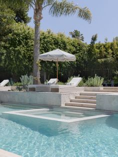 an outdoor pool with lounge chairs, umbrella and steps leading up to the swimming pool