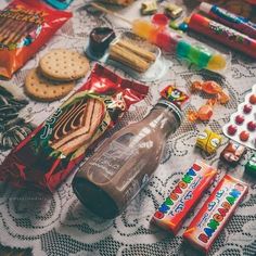 a table topped with lots of different types of snacks and candy bar wrappers on top of a doily