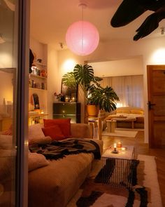 a living room filled with furniture next to a window covered in plants and candles on top of rugs