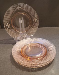 an empty glass plate sitting on top of a counter next to a silver bowl and saucer