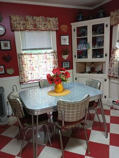 a kitchen with red and white checkered flooring has a dining room table surrounded by chairs