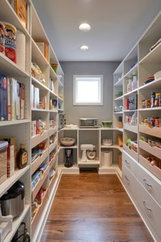 an organized pantry with white shelving and lots of food on the shelves, along with wooden flooring