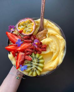 a hand holding a bowl filled with fruit