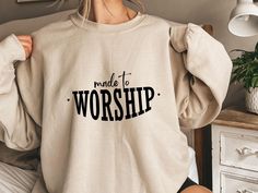 a woman wearing a sweatshirt with the words made to worship printed on it in black