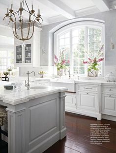 a large kitchen with white cabinets and an island in front of a window that has flowers on it