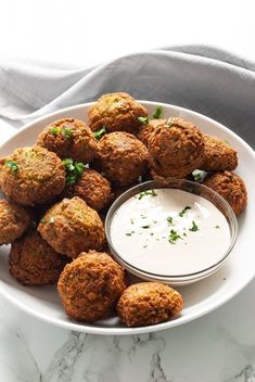 a white plate topped with fried food next to a small bowl of ranch dressing on top of it