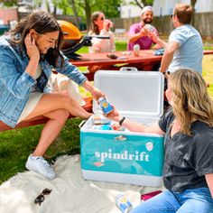 a woman sitting on a bench next to a cooler