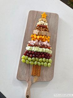 a christmas tree made out of grapes and crackers on a cutting board with a wooden spoon