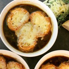 three bowls filled with soup and meatballs on top of a table next to bread