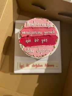 a pink cake in a cardboard box with writing on the top and bottom part,