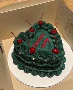 a green cake with cherries on it in a box