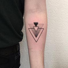 a black and white photo of a person's arm with a triangle tattoo on it